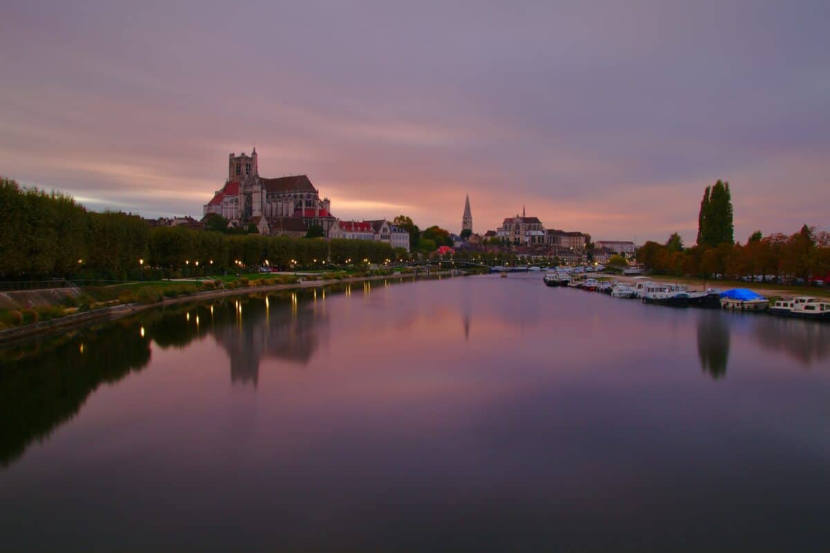 A cidade de Auxerre na França, um castelo ao lado de um rio ao entardecer