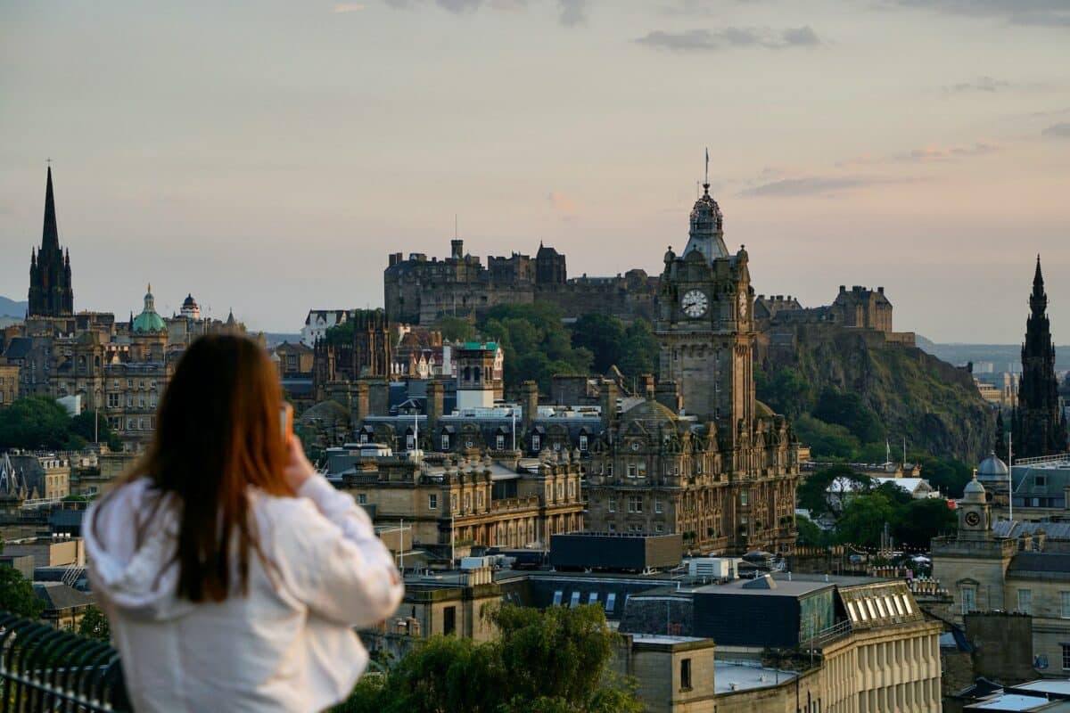 Calton Hill, Edinburgh. Foto: Stuart Hay via Unsplash. Mulher de costas olhando para a cidade