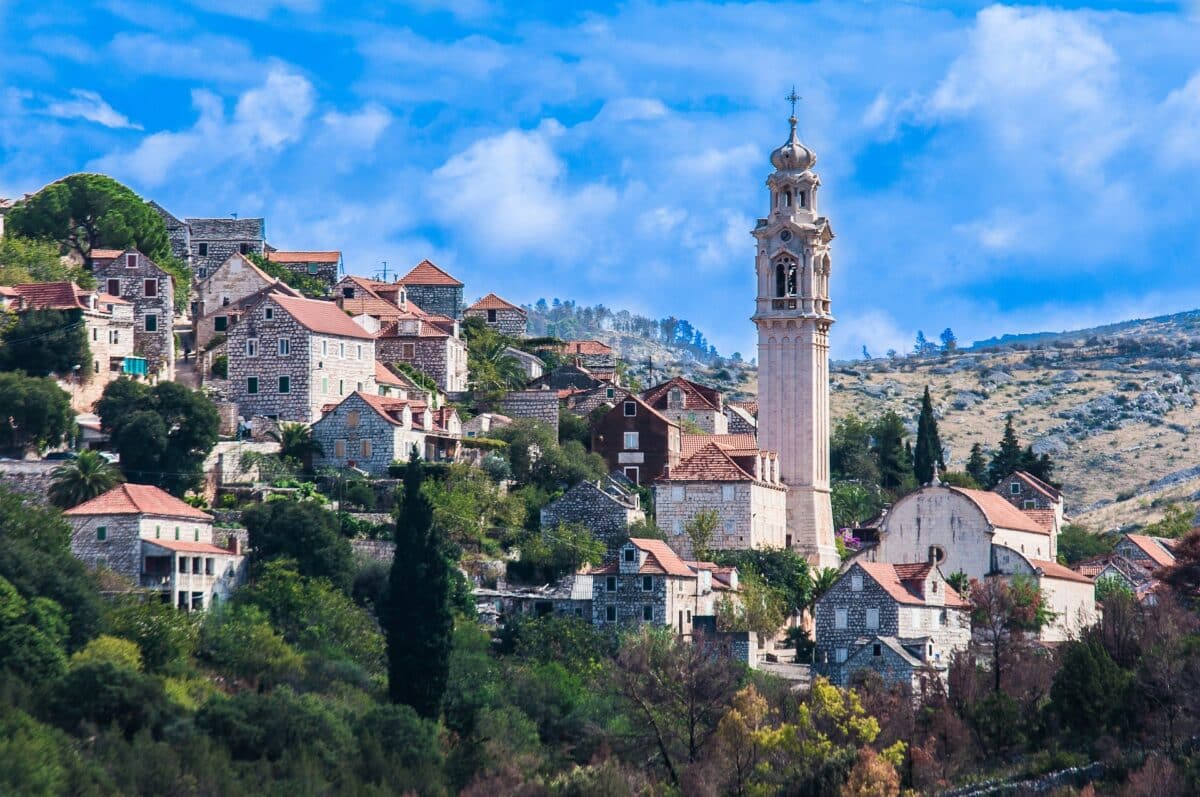 Foto da ilha de Brac na Croacia. Vilarejo na montanha com uma torre de igreja
