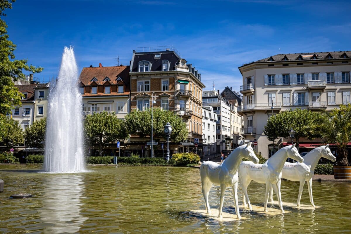 CEntro da cidade de Baden-Baden, fonte de agua com cavalos branco . Ao fundo casario antigo com arvores verdes