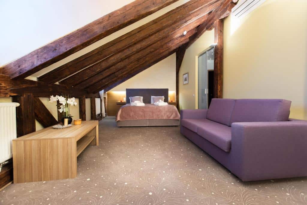 Hotel Boutique Bern - quarto de casal em tons de lilás, com sofá e mesa