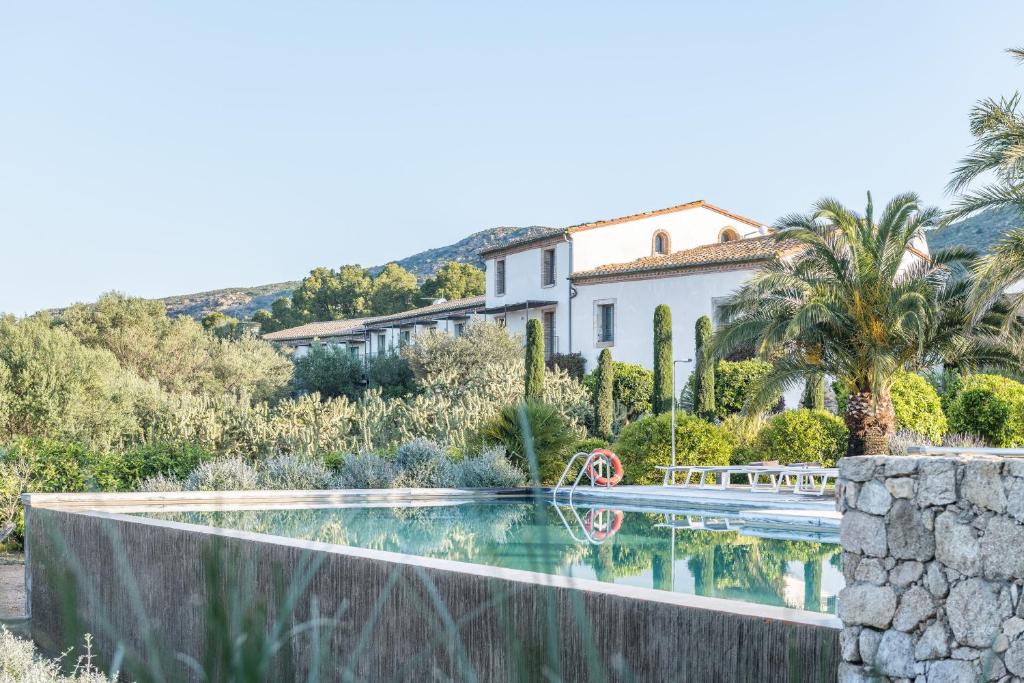 Hotel Mas Lazuli na Costa Brava na Espanha. Vista externa com piscina, mata verde e casa branca em estilo colonia.