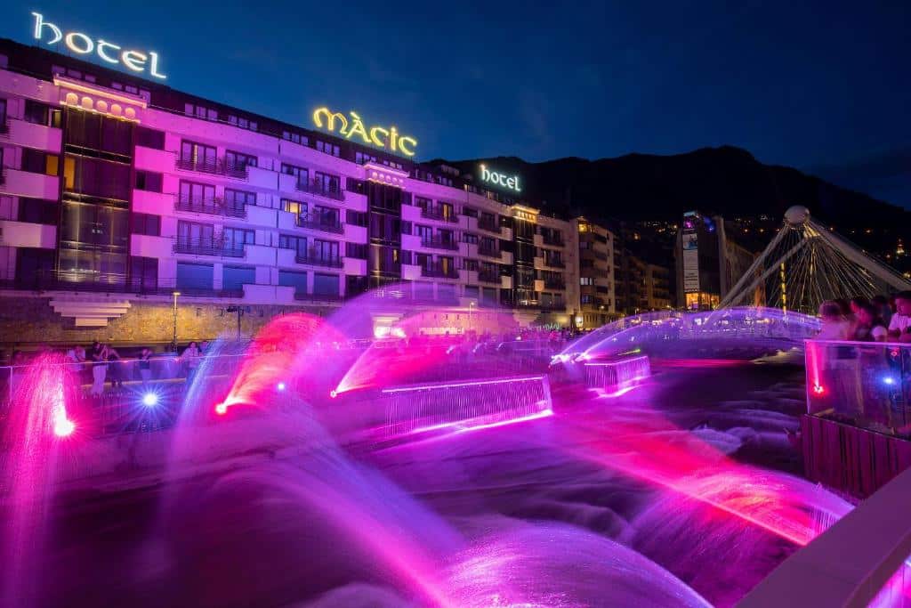 Vista externa do Hotel Màgic Andorra 
faixada toda colorida com luzes roxa e vermelha.