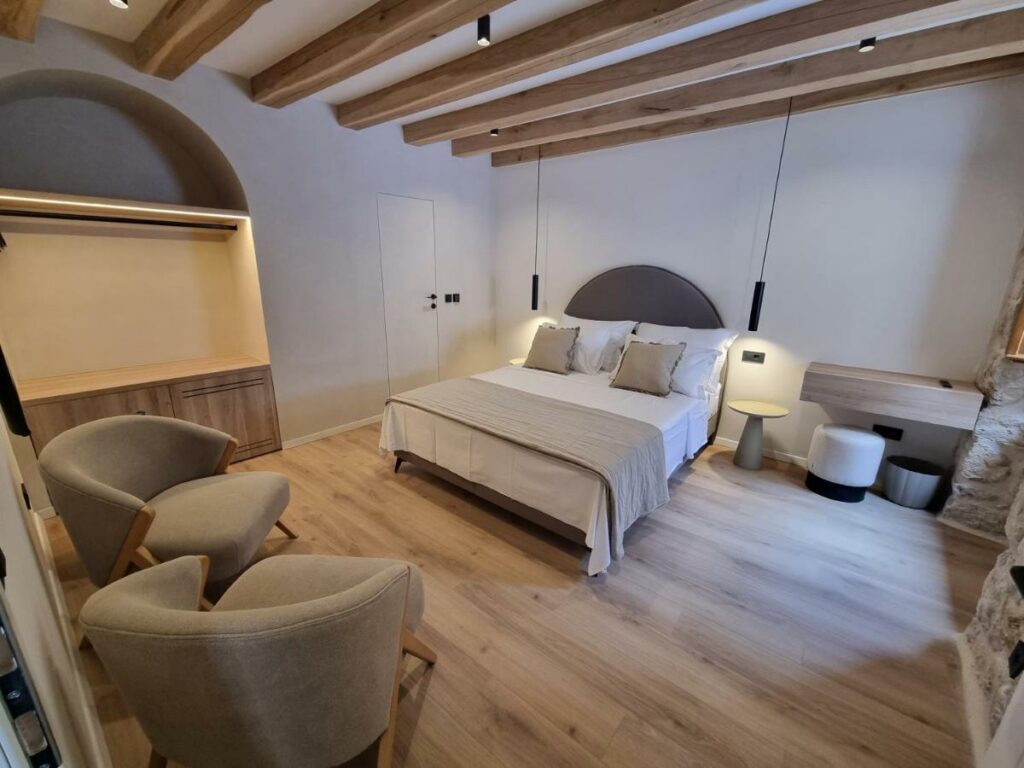 Quarto com cama de casal, luminarias, poltronas, muito aconchegante. A imagem representa um dos locais de Dubrovnik, na Croacia.
