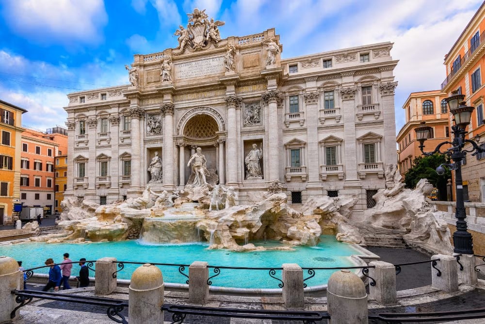 Fontana di Trevi, é possível ver a fonte com estátuas romanas atrás, uma construção tipicamente barroca. Está localizada no rione Trevi, em Roma. A fonte está encostada na fachada do Palazzo Poli, que têm janelas grandes, e adornos característicos da arquitetura barroca.