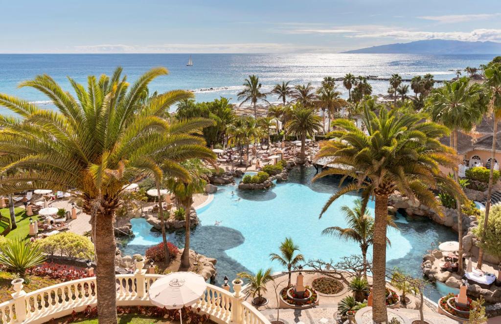 Vista do Hotel Bahia del Duque em Adeje, nas ilhas Canárias. Piscina em meio a coqueiros e ao fundo o mar. 