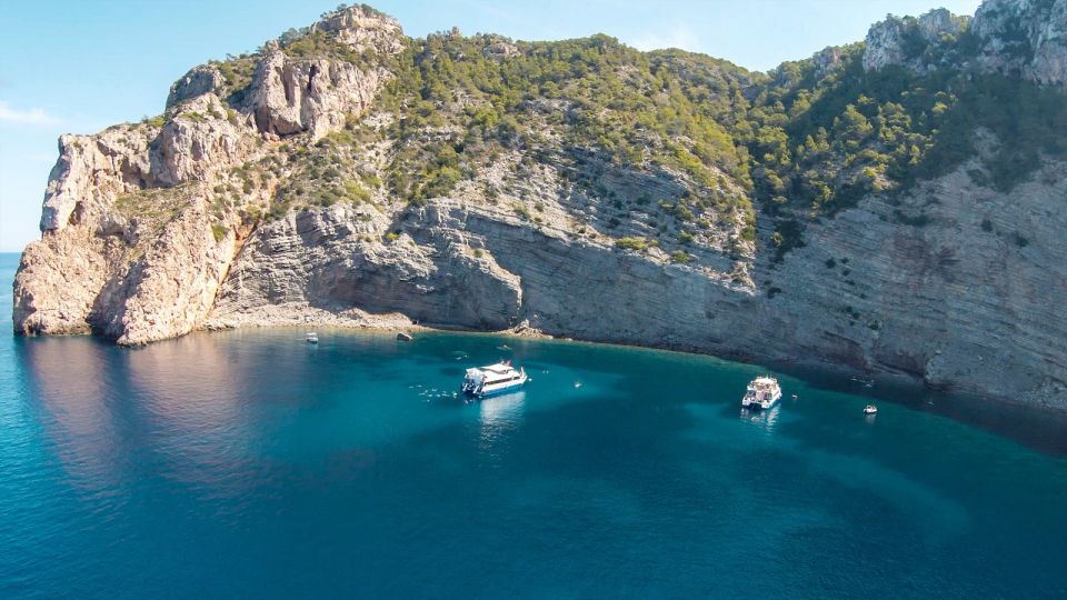 parte norte de Ibiza, onde se destacam Cala Saladeta e o arquipélago de Ses Margalides, na foto. Mar azul turquesa, com dois barcos próximo a uma encosta. 
