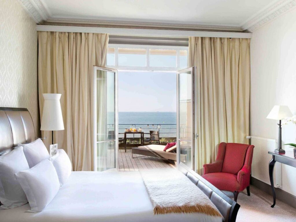 Quarto com cama de casal, bem aconchegante com vista para o mar do Le Grand Hotel Cabourg na Normandia.