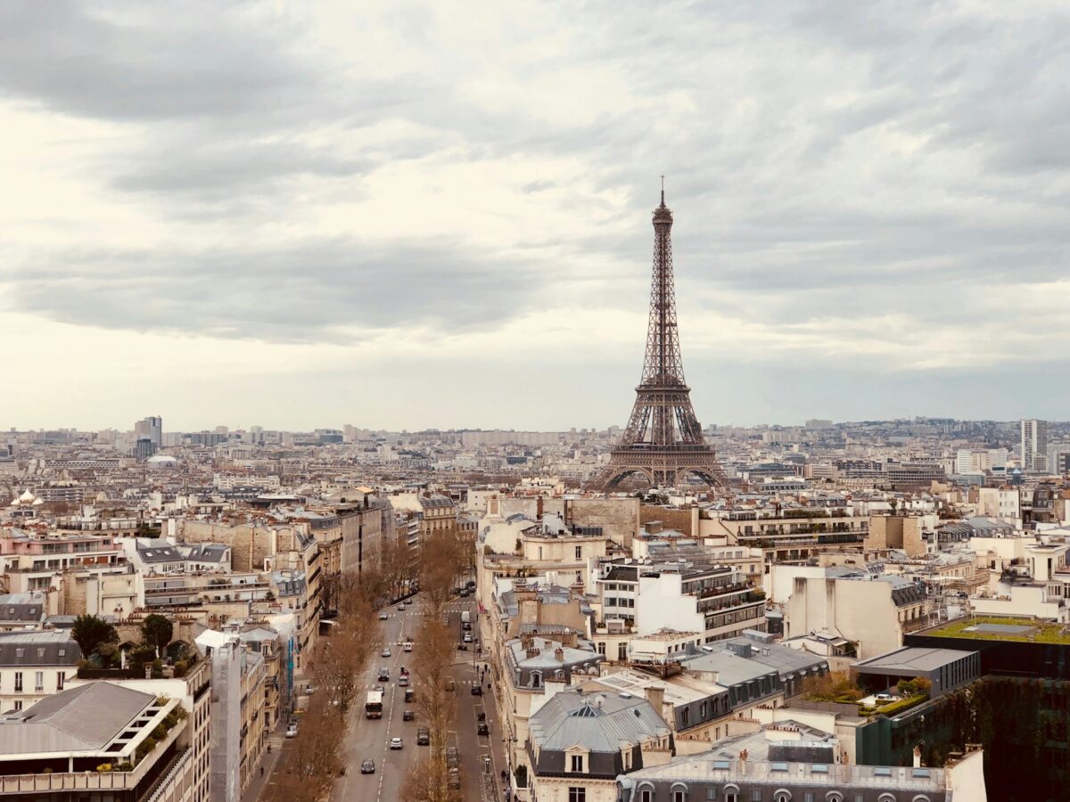 Vista aérea de Paris com a Torre Eiffel no centro, cercada por edifícios sob um céu nublado, para representar seguro viagem para Paris